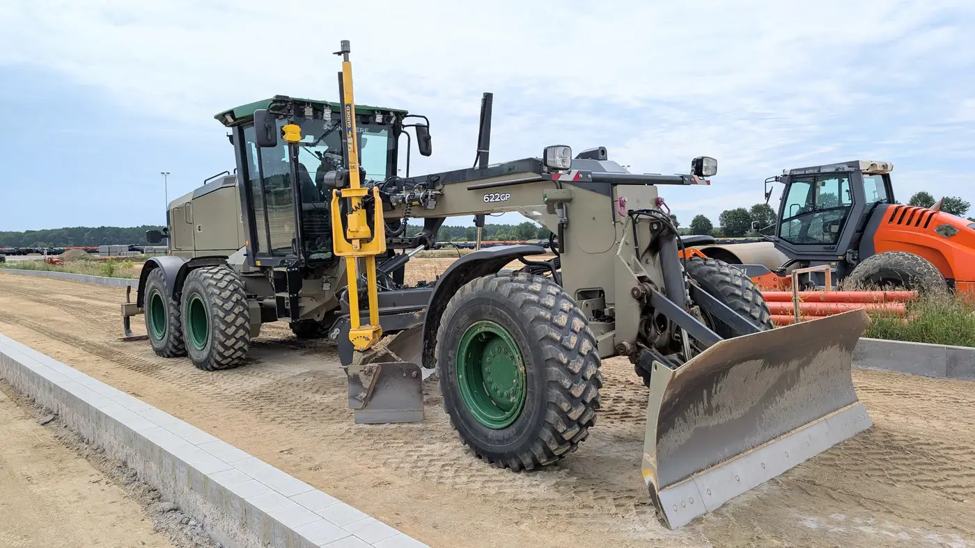 A road grader with a GPS guidance mast working on a construction site.
